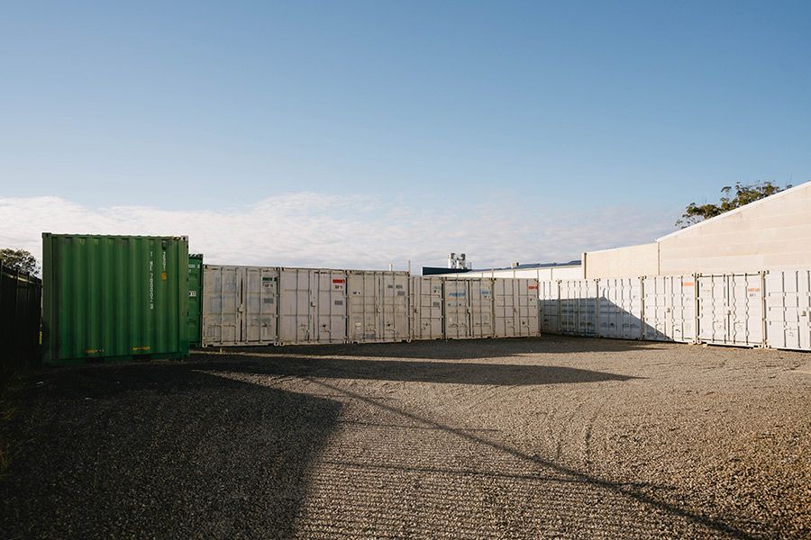 Green and White Storage Containers in a Gravel Lot Under a Blue Sky — Easy Choice Removals and General Freight In Wollongong, NSW