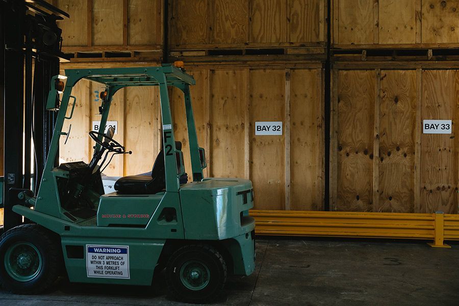 Green Forklift in Warehouse With Wooden Storage Crates — Easy Choice Removals and General Freight In Macquarie, NSW
