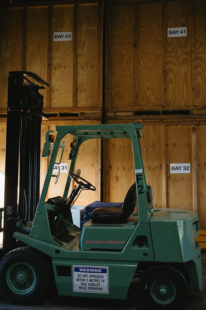 Green Forklift In A Warehouse With Wooden Storage Units — Easy Choice Removals and General Freight In Southern Hinterlands, NSW