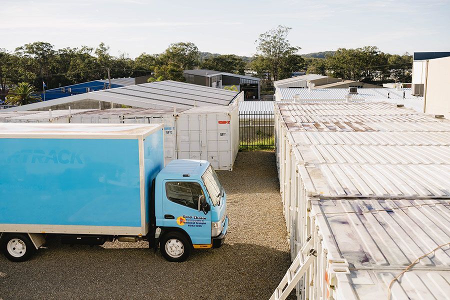 Blue Truck Parked Near Storage Containers in an Outdoor Lot — Easy Choice Removals and General Freight in Newcastle, NSW