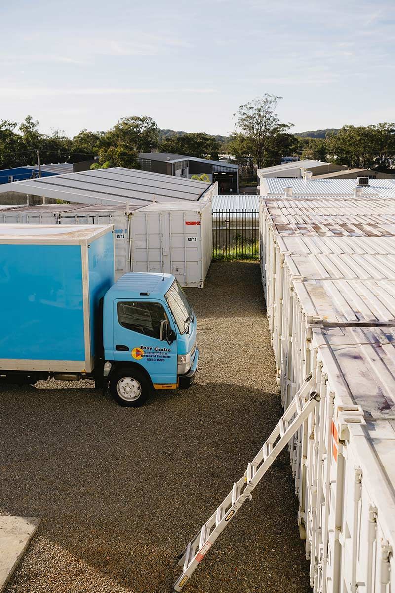 Blue Truck Parked Near Storage Containers — Easy Choice Removals and General Freight in Newcastle, NSW