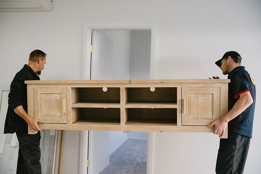 Two Men Carrying a Light Brown Wooden — Easy Choice Removals and General Freight In Brisbane, QLD