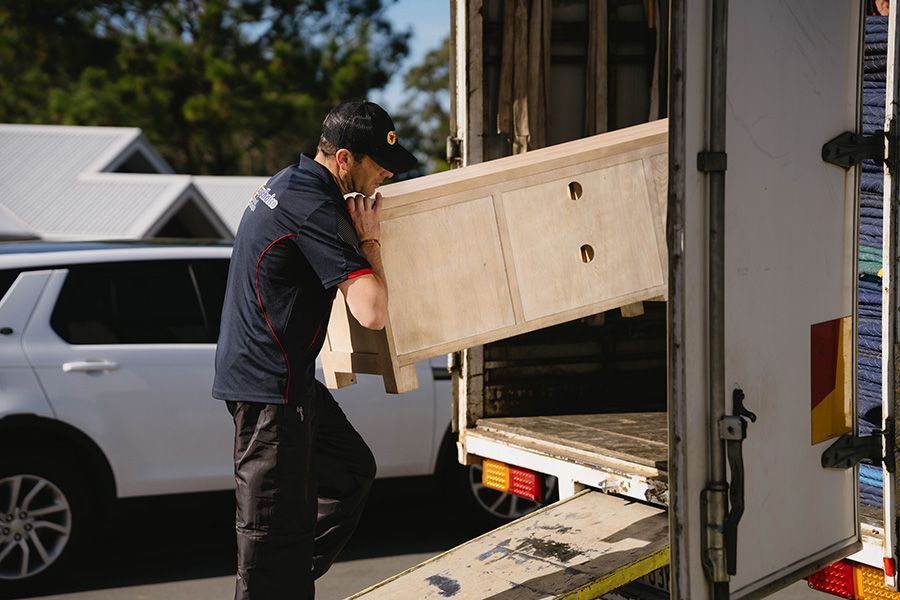 Moving Service Worker Carrying a Wooden Cabinet — Easy Choice Removals and General Freight in Sydney, NSW