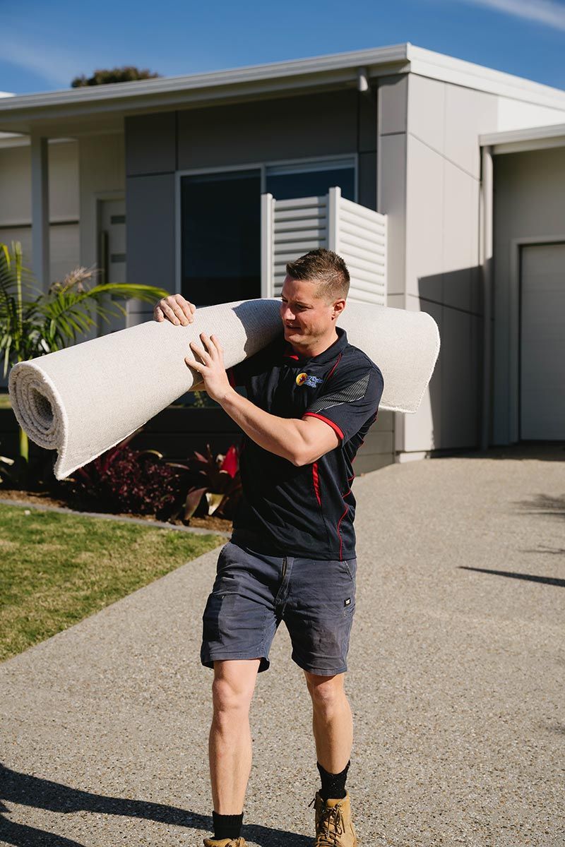 Man Carrying A Rolled-up Carpet On His Shoulder Outdoors — Easy Choice Removals and General Freight In Mid North Coast, NSW