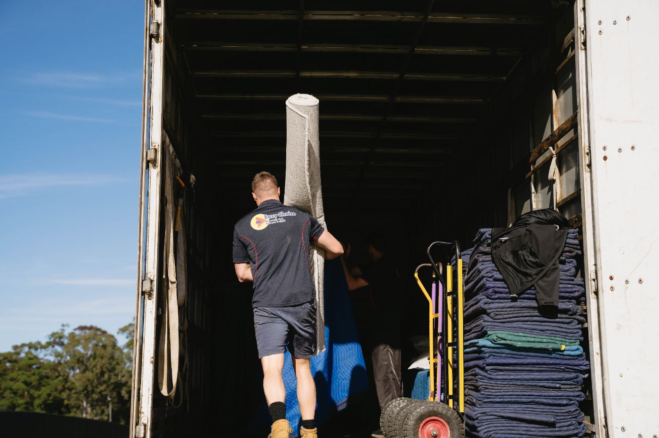 A Person is Taping a Box With Yellow Tape — Easy Choice Removals and General Freight in Coffs Harbour, NSW