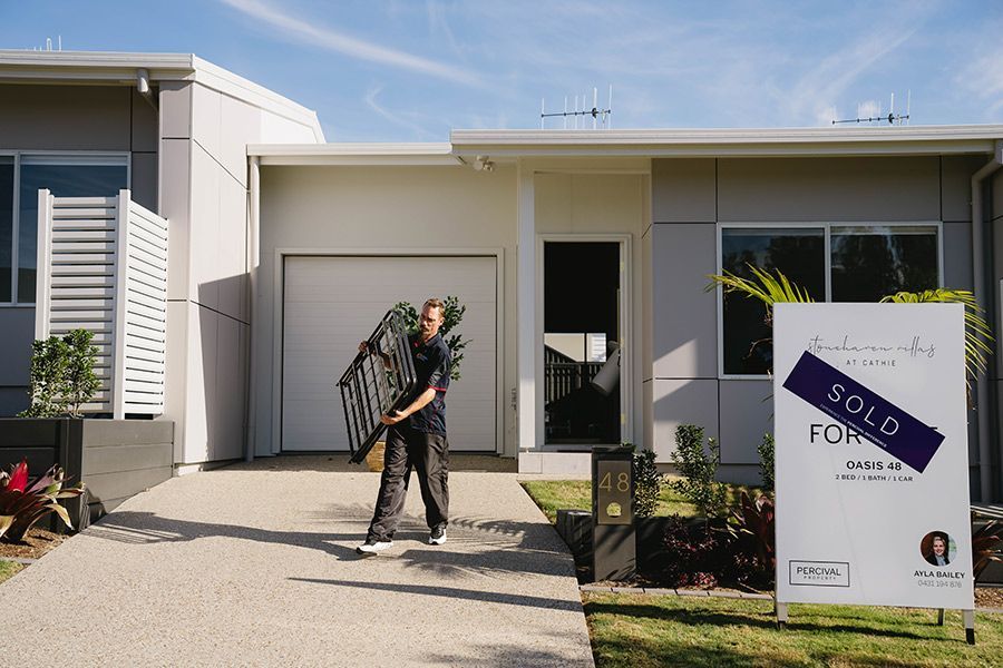 Man Carrying Objects in Front of a Modern Home — Easy Choice Removals and General Freight In Port Macquarie, NSW