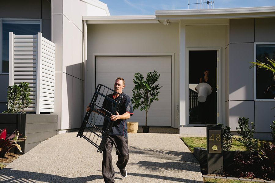 Man Carrying a Metal Frame Towards a House — Easy Choice Removals and General Freight in Tweed Heads, NSW
