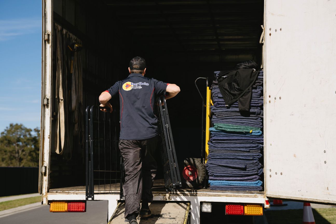 Man Loads a Truck With Stacked Moving Pads and Metal Equipment — Easy Choice Removals and General Freight in Byron Bay, NSW