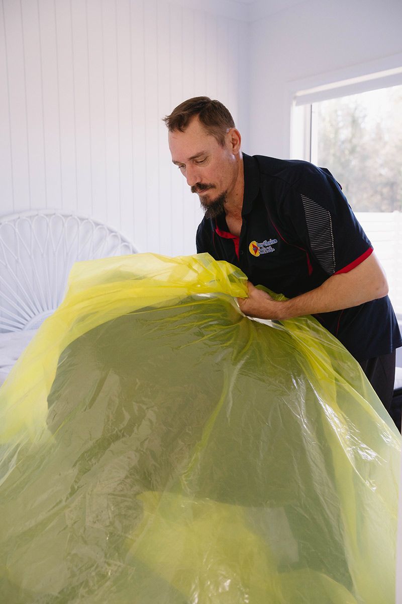 Man In Black Shirt Securing A Large Green Item In A Yellow Bag — Easy Choice Removals and General Freight In Port Macquarie, NSW