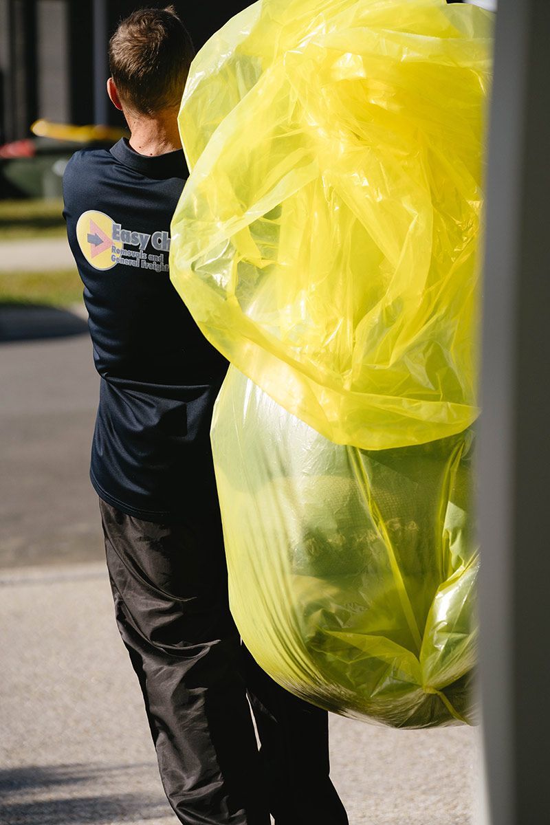 Man Carrying Large, Full Yellow Trash Bag Outdoors — Easy Choice Removals and General Freight In Brisbane, QLD
