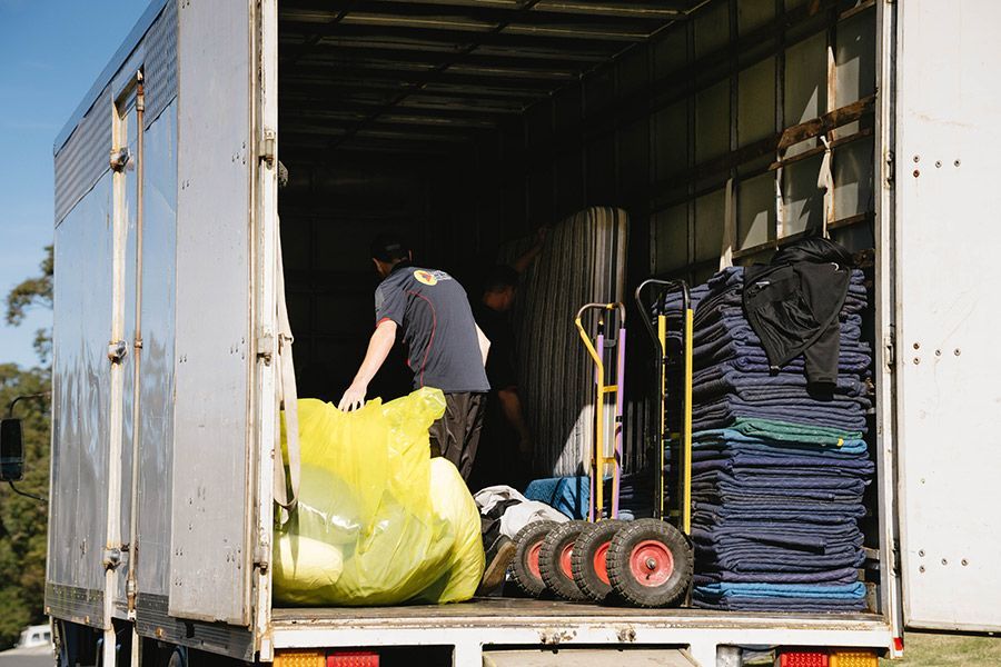 Two Movers Loading A Truck With A Yellow Bag And Other Items — Easy Choice Removals and General Freight In Port Macquarie, NSW