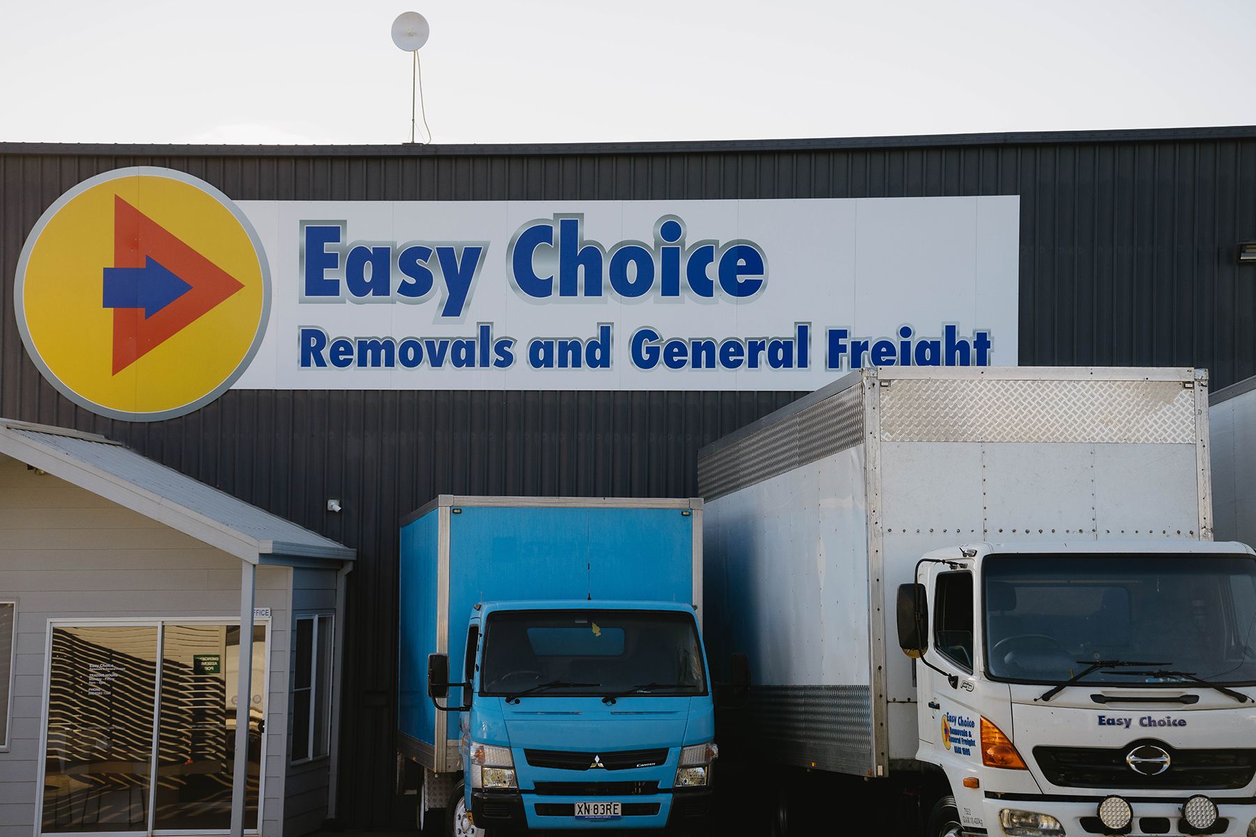 A Moving Truck is Parked in Front of a Tall Building — Easy Choice Removals and General Freight In Port Macquarie, NSW