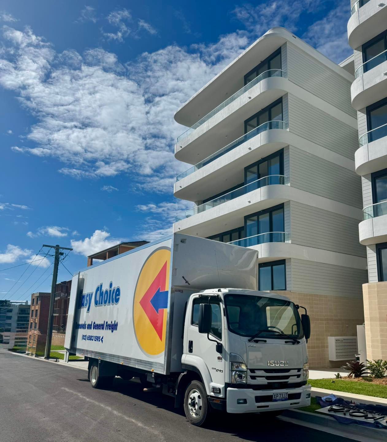 White Moving Truck Parked Beside Modern Apartment Building