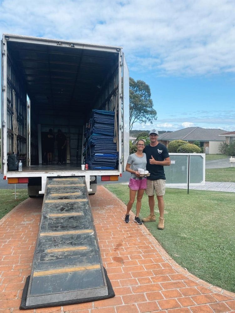 A Man and a Woman Are Standing in Front of a Moving Truck — Easy Choice Removals and General Freight In Port Macquarie, NSW