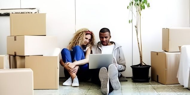 A Man and a Woman Are Sitting on the Floor Looking at a Laptop — Easy Choice Removals and General Freight In Port Macquarie, NSW