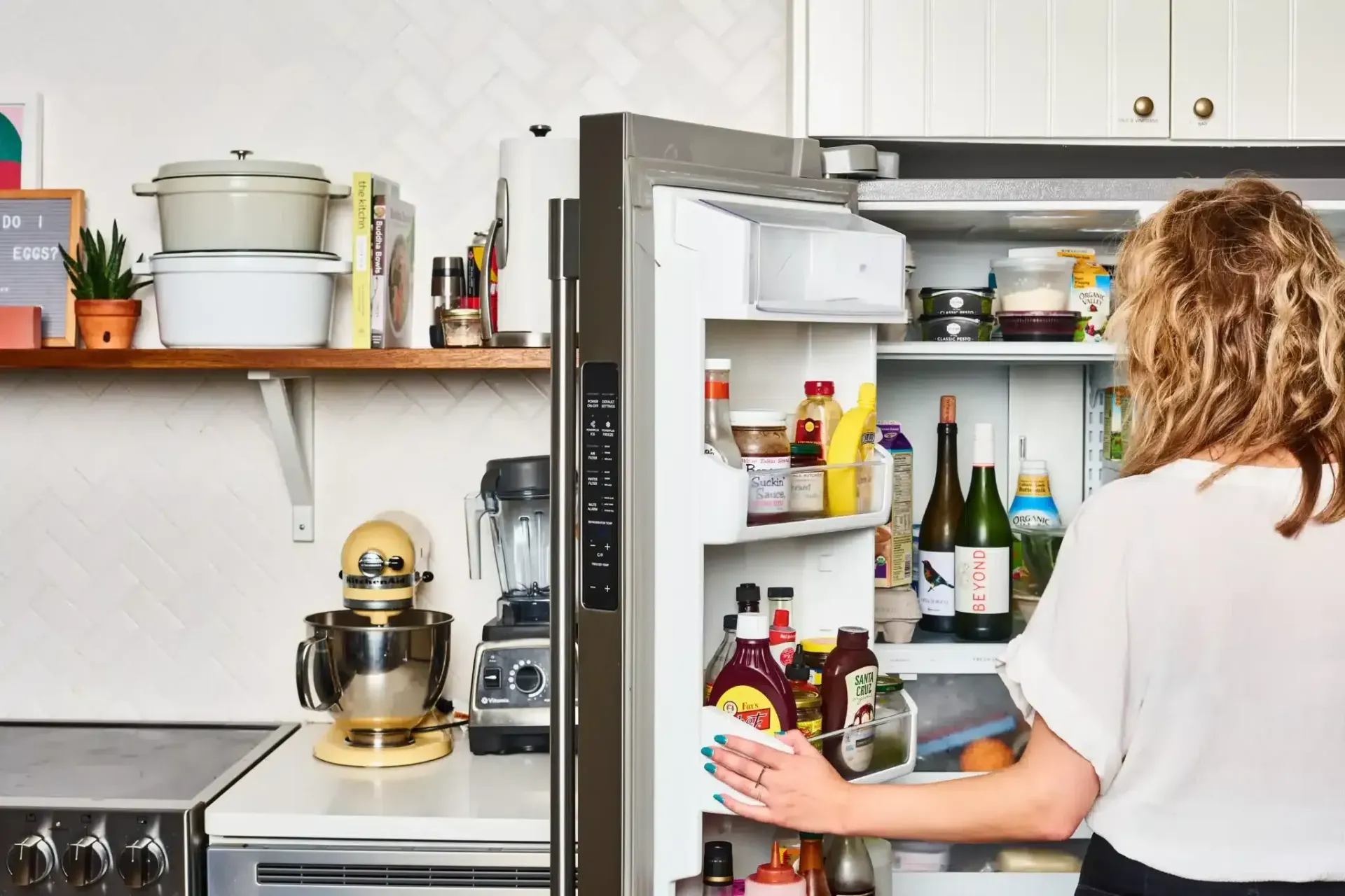 A Woman is Opening a Refrigerator Door in a Kitchen — Easy Choice Removals and General Freight In Port Macquarie, NSW
