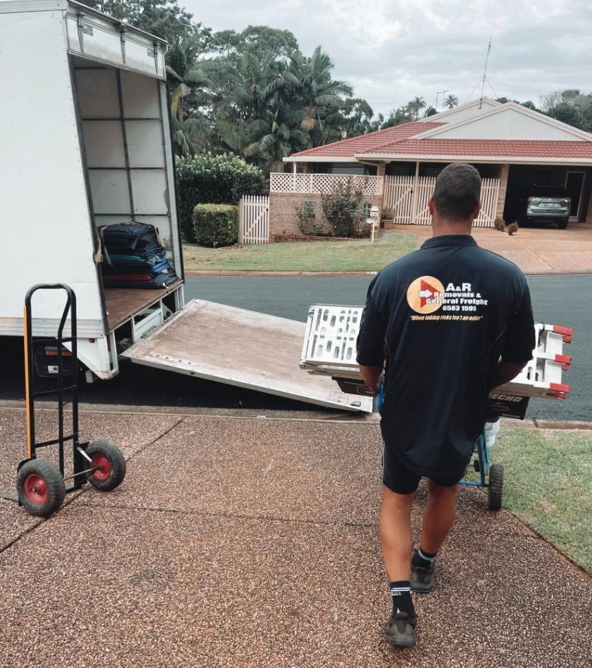 A Man is Pushing a Dolly Down a Sidewalk — Easy Choice Removals and General Freight In Port Macquarie, NSW.