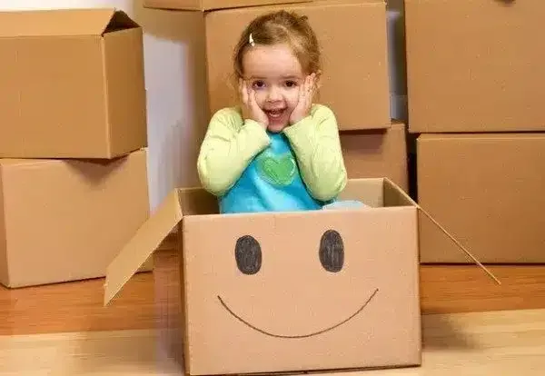 A Little Girl is Sitting in a Cardboard — Easy Choice Removals and General Freight In Port Macquarie, NSW