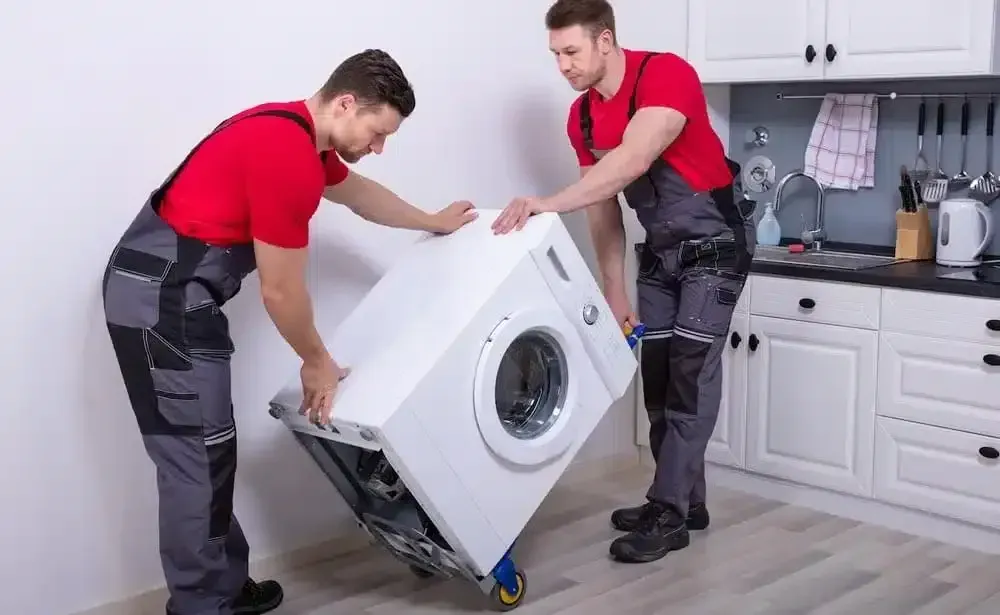 Two Men Are Carrying a Washing Machine on a Dolly in a Kitchen — Easy Choice Removals and General Freight In Port Macquarie, NSW