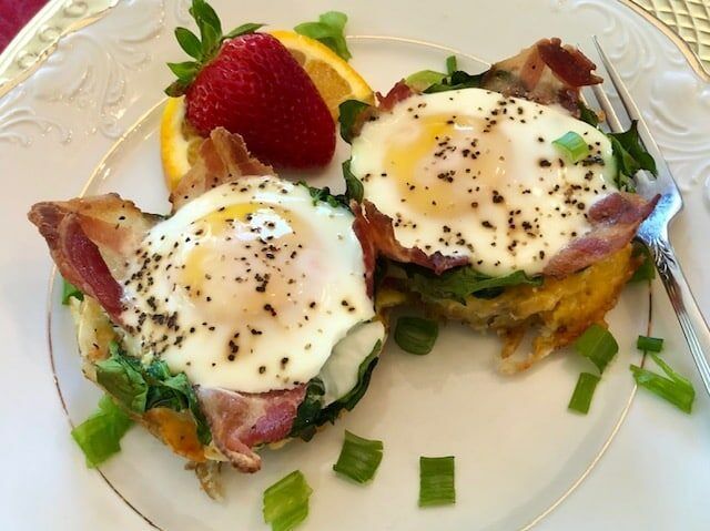 A white plate topped with eggs bacon and strawberries