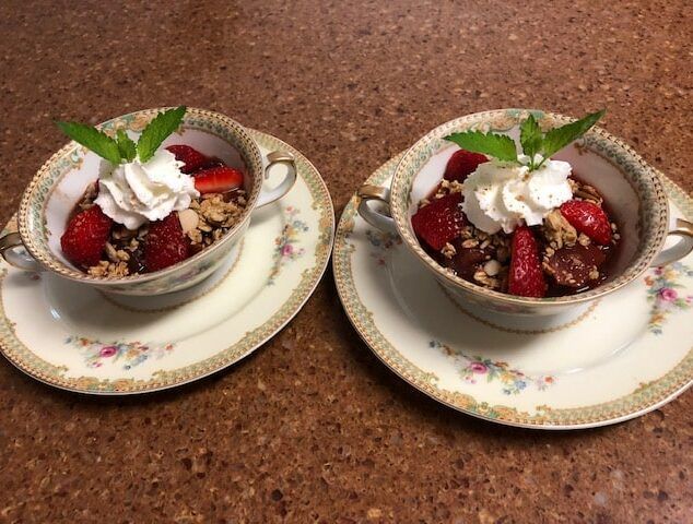 Two cups of dessert with whipped cream and strawberries on top