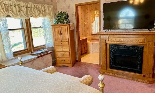 A bedroom with a fireplace and a flat screen tv.
