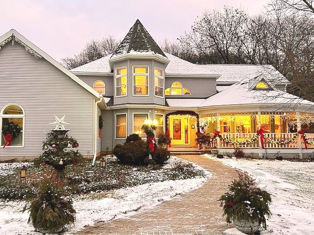 A large house is covered in snow and decorated for christmas