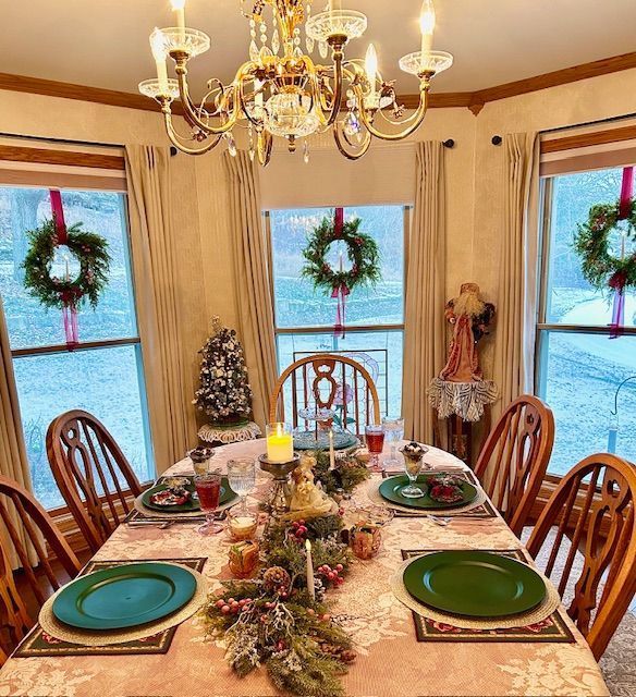 A dining room table with plates , candles , and a chandelier.