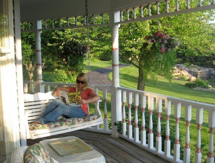 A woman sits on a porch swing reading a book
