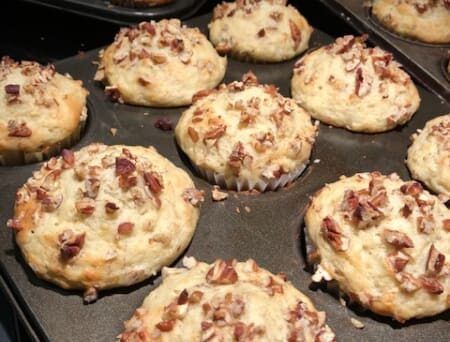 A pan filled with muffins with pecans on top