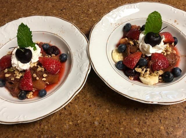 Two bowls of fruit with whipped cream and mint leaves on top