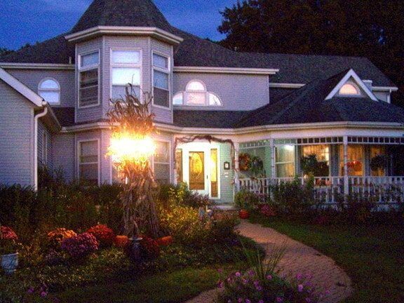 A large house with a porch is lit up at night