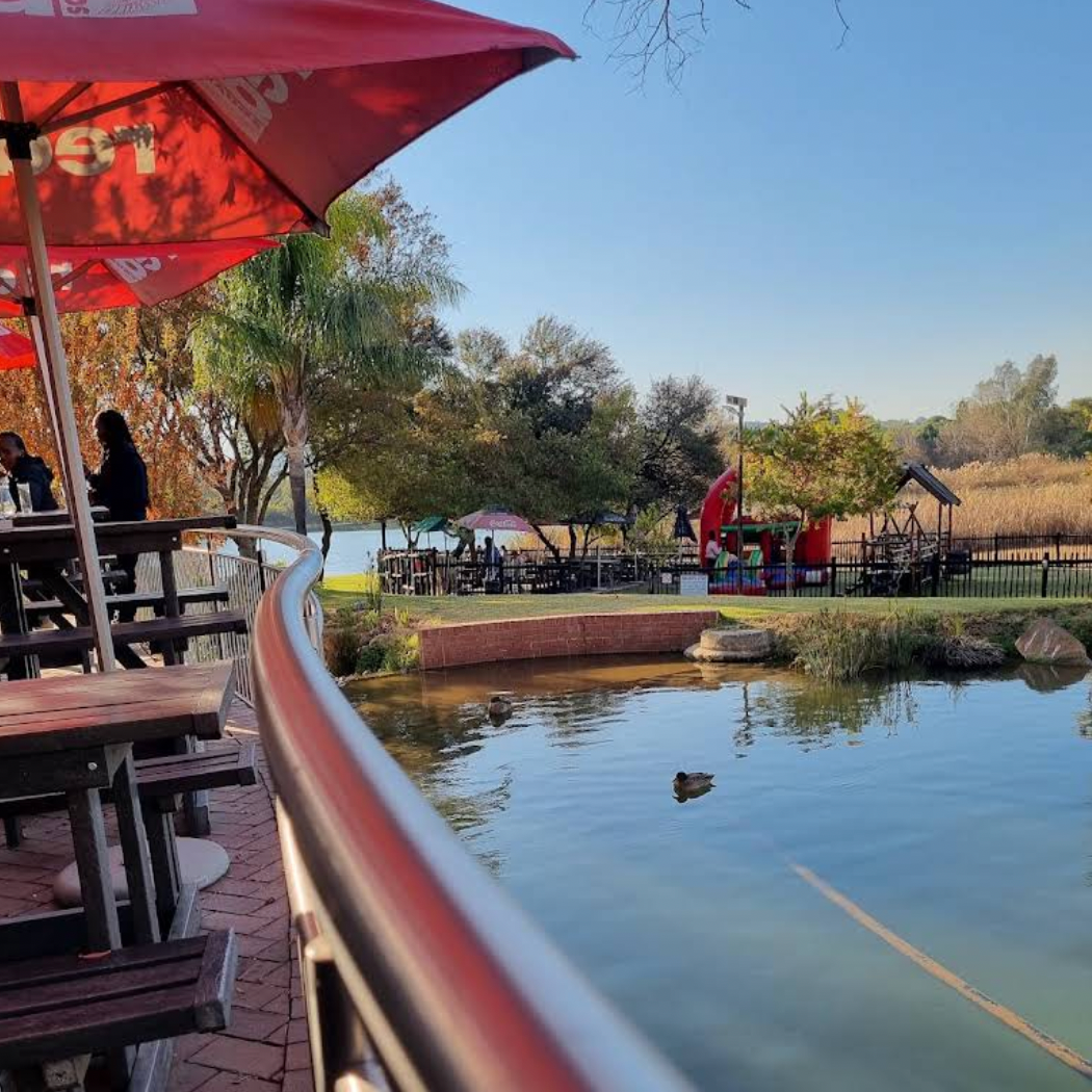A picnic area with tables and umbrellas overlooking a lake