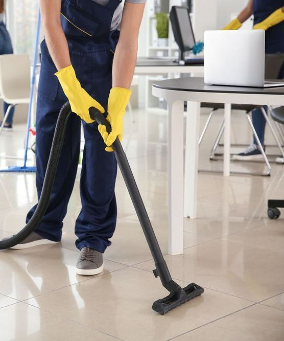 A Man Wearing Yellow Gloves Is Using A Vacuum Cleaner In An Office — Super Home Cleaning Services In Manunda, QLD