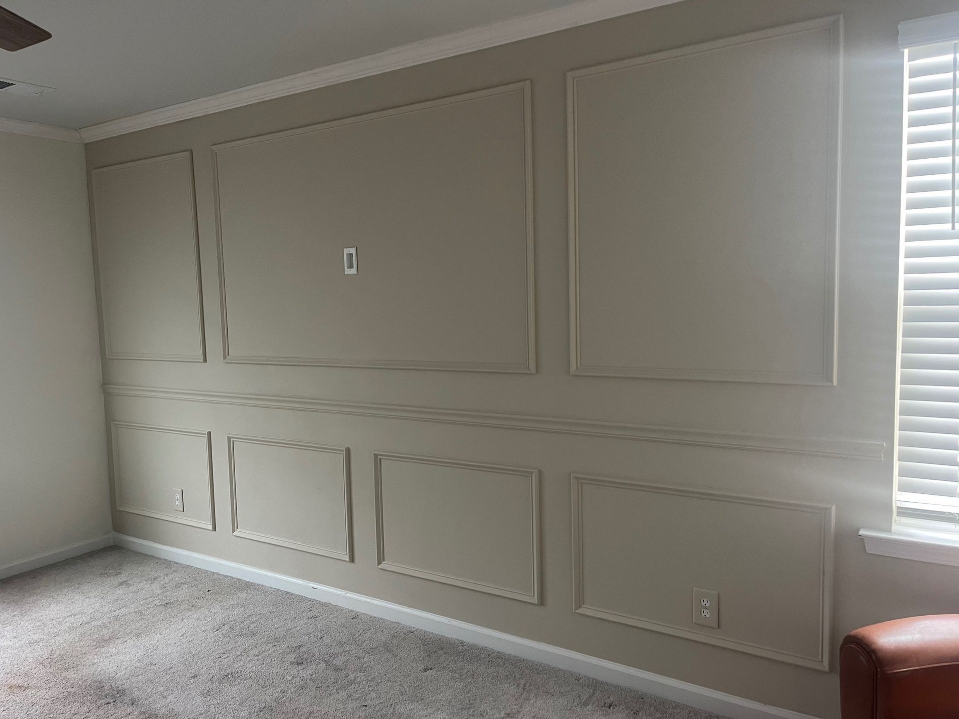 White panel molding on a wall with matching white wood flooring.