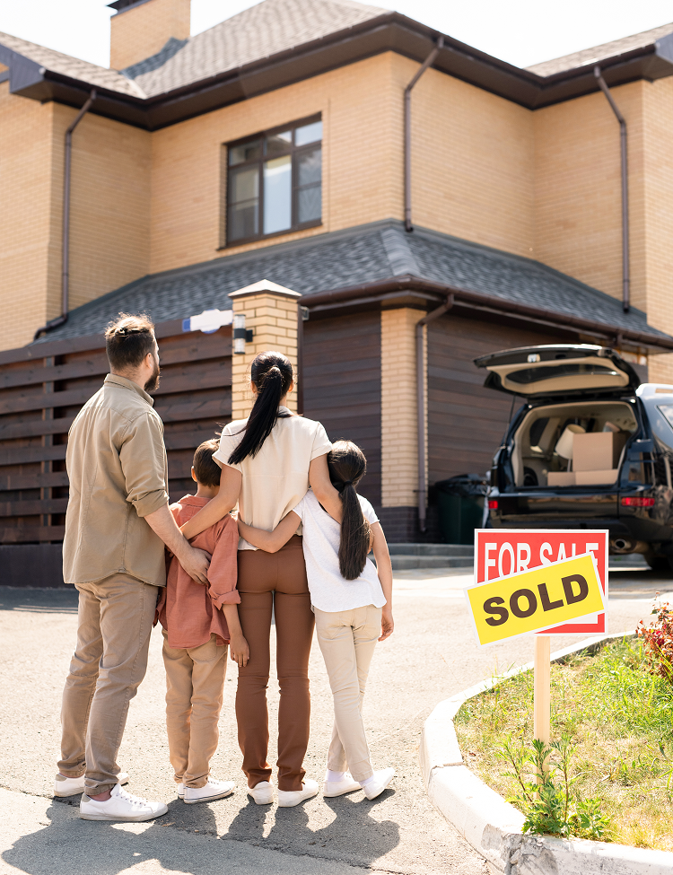 Family of four standing in front of a house, with 