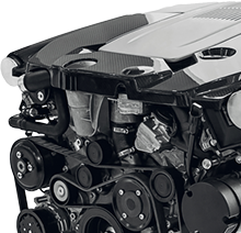 Close-up of a car engine with visible belts, pulleys, and carbon-fiber cover | CB Warren's Auto Care