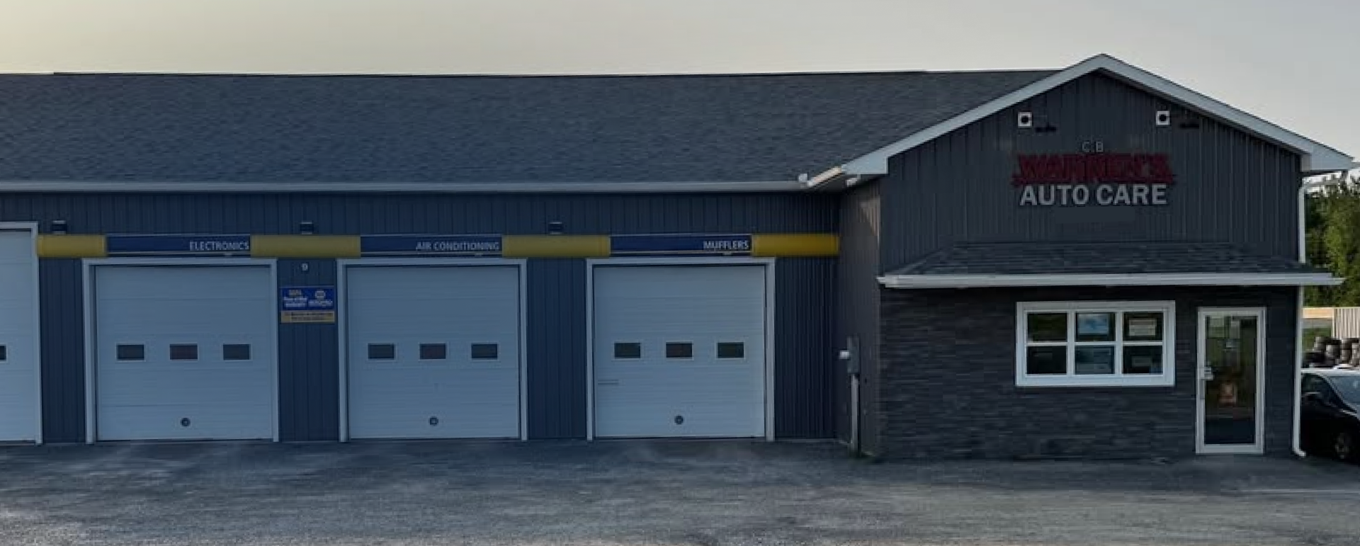 Auto care garage with three white bay doors and a dark storefront | CB Warren's Auto Care
