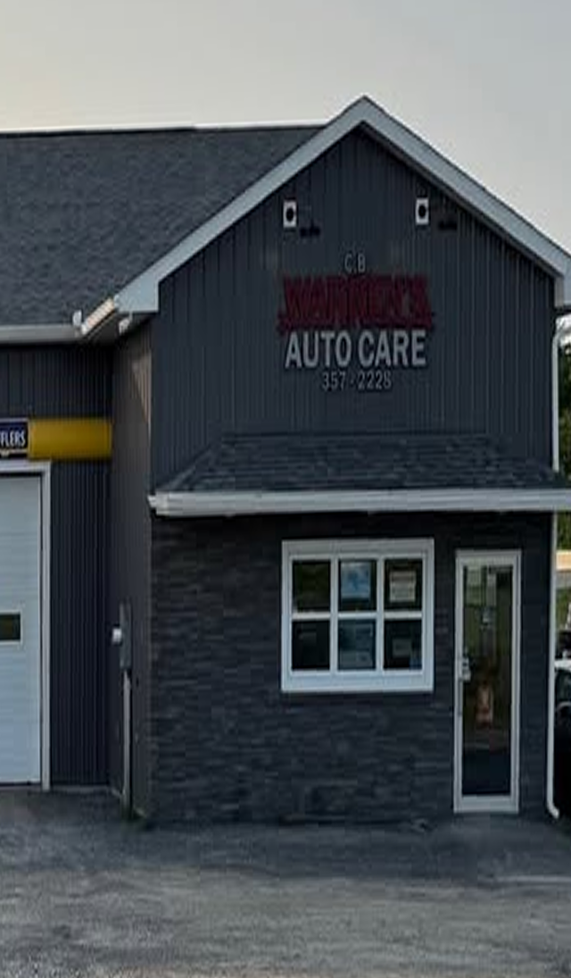 Auto care shop exterior with gray siding, dark stone base, and white-trimmed windows | CB Warren's Auto Care