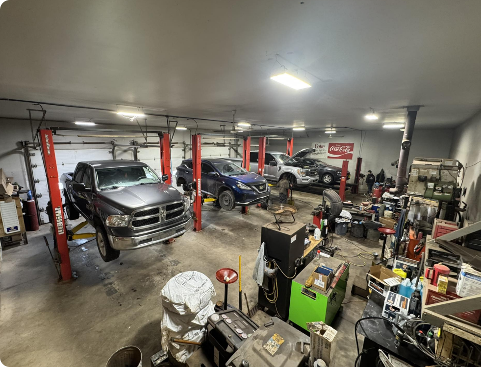 Auto repair shop with two vehicles on lifts and tools cluttering the garage floor | CB Warren's Auto Care