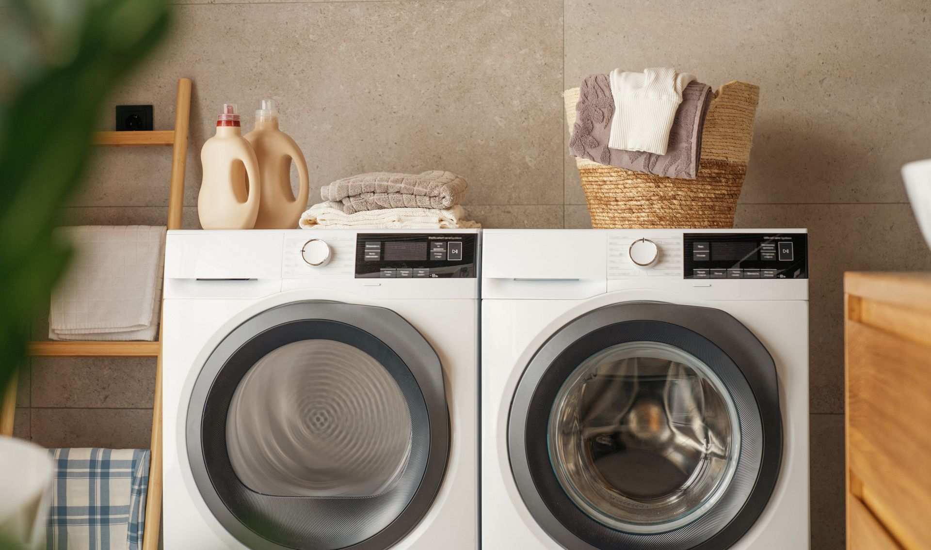 Laundry room with white washer and dryer, laundry supplies, and a basket of towels.