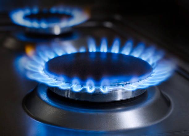 A stove burner lit with bright blue flames, showing the heat from natural gas.