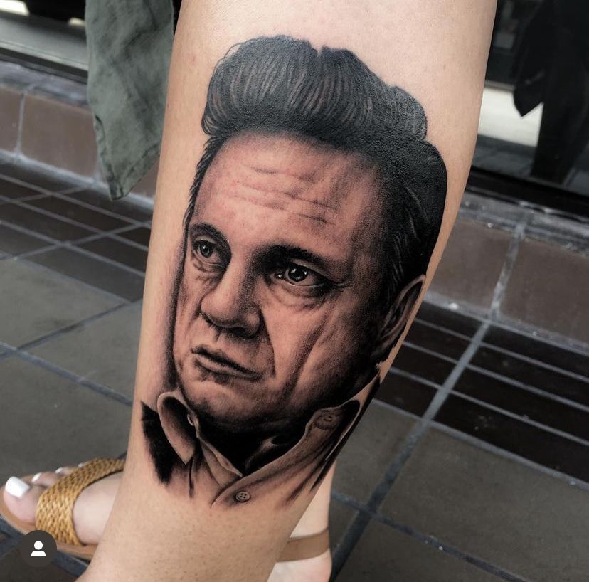 Black-and-gray tattoo portrait of a man's face on a forearm