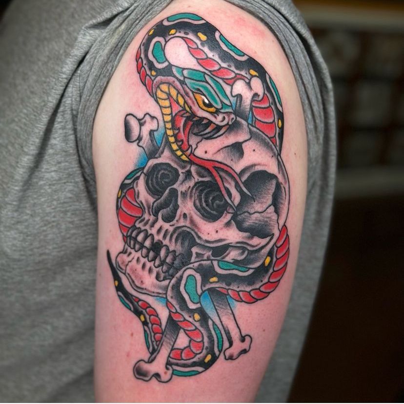 Colorful snake and skull tattoo on an upper arm with bold black, red, pink, and blue ink
