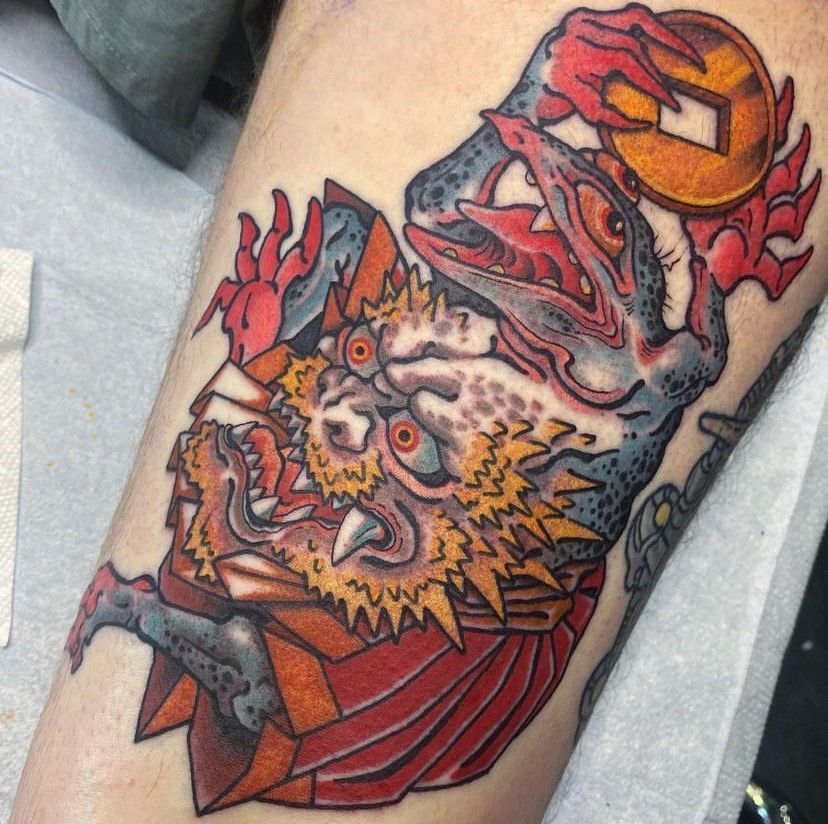 Colorful owl tattoo with red wings and orange eyes on a person’s forearm