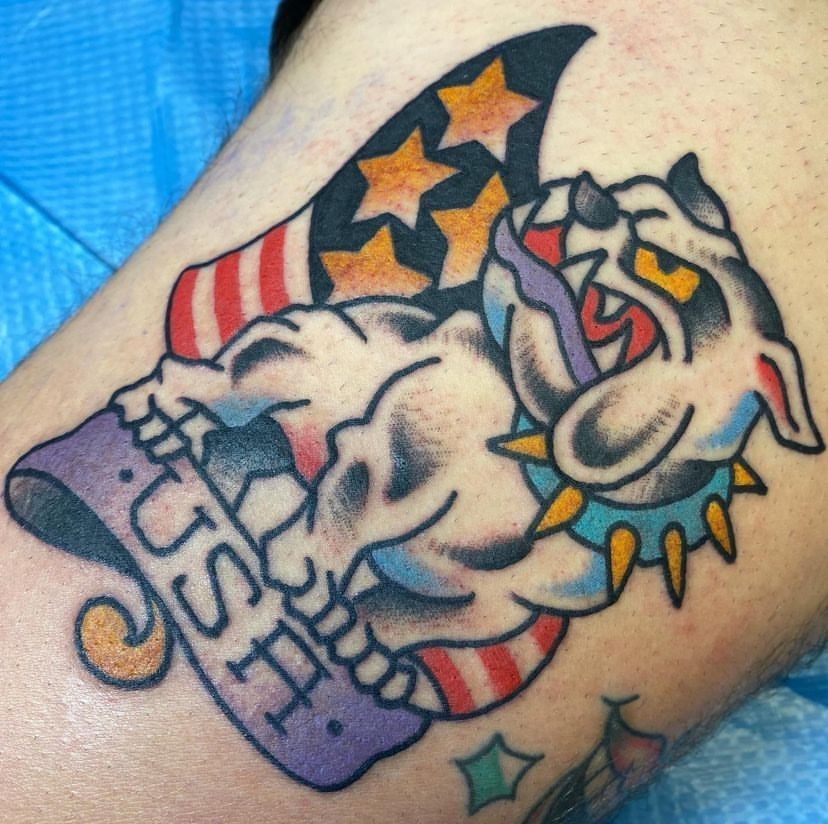 Colorful tattoo of a snarling bulldog with stars, stripes, and a chain on skin