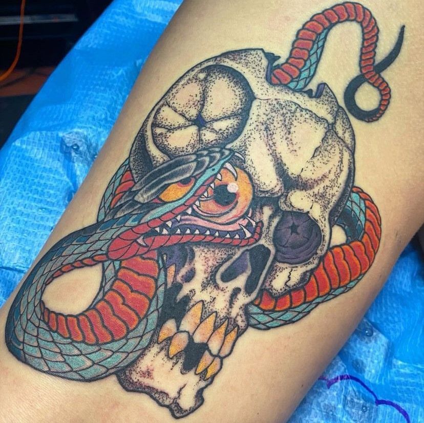 Skull and red snake tattoo on a person's leg, with dark shading and detailed linework