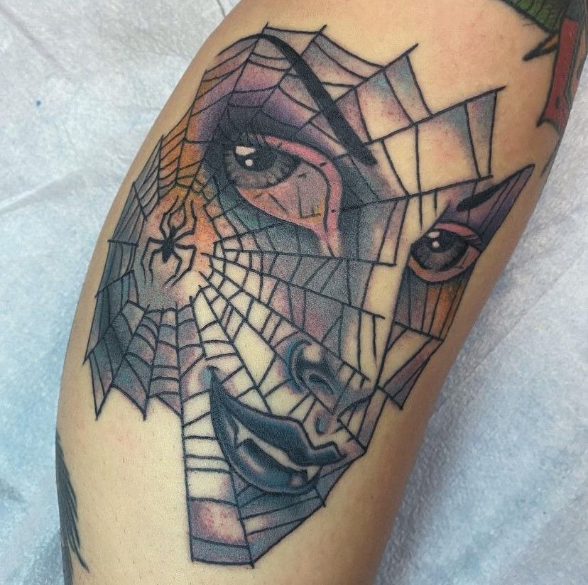 Close-up of a colorful spiderweb face tattoo on skin, with eyes and lips in the design