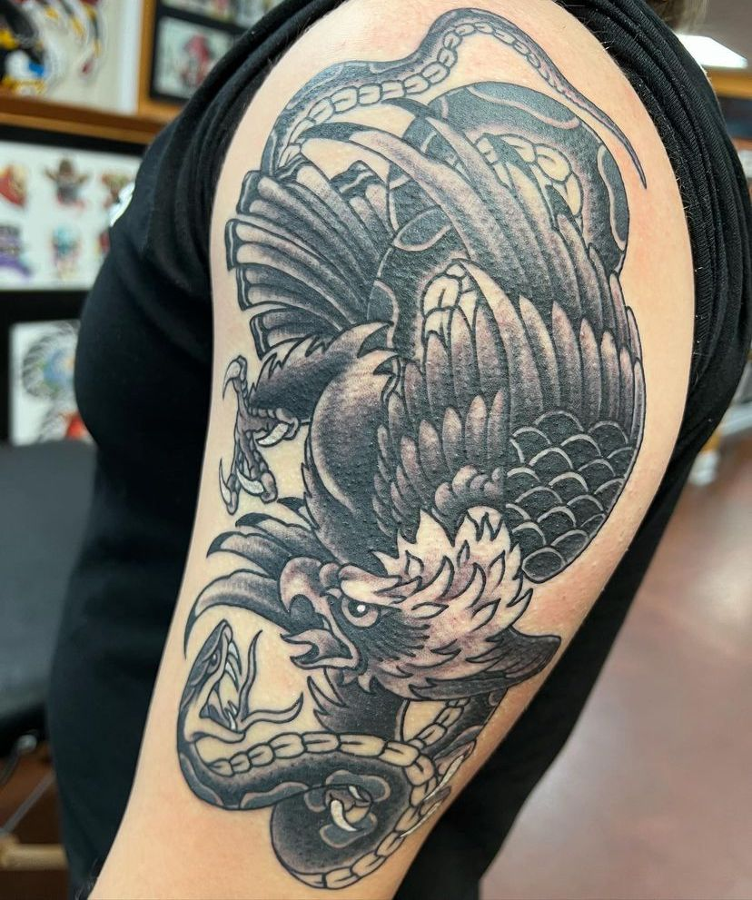 Black-and-gray dragon tattoo on an upper arm, with intricate scales and swirling clouds