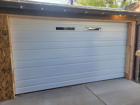 A white, horizontal-panel garage door installed in a wooden frame with two small, rectangular windows at the top.